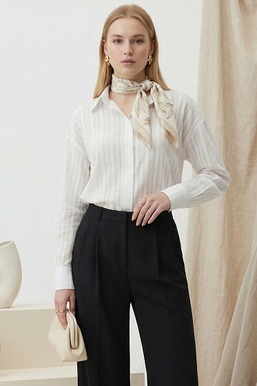 Elegant longline shirt featuring a relaxed fit, dropped shoulders, and a stand-up collar. A pleated back yoke adds a sophisticated architectural touch. This versatile wardrobe staple seamlessly transitions from casual to polished office looks.