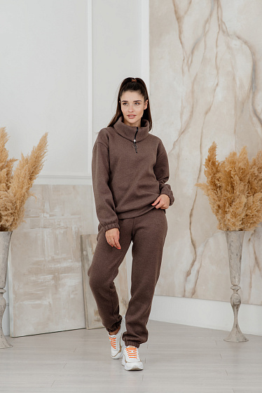 Knitted jersey suit. High collar sweatshirt with zip top, low shoulder line, elasticated sleeve bottom. Joggers on the elastic waistband with side pockets.  Slightly tapered trousers with elastic band at the bottom.