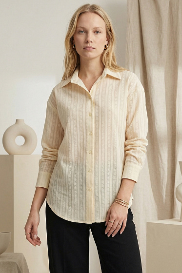 Elegant longline shirt featuring a relaxed fit, dropped shoulders, and a stand-up collar. A pleated back yoke adds a sophisticated architectural touch. This versatile wardrobe staple seamlessly transitions from casual to polished office looks.