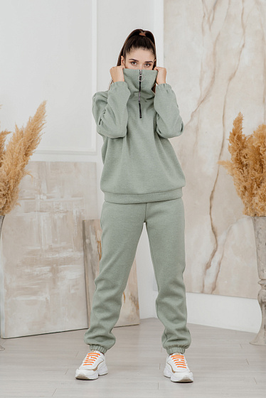 Knitted jersey suit. High collar sweatshirt with zip top, low shoulder line, elasticated sleeve bottom. Joggers on the elastic waistband with side pockets.  Slightly tapered trousers with elastic band at the bottom.