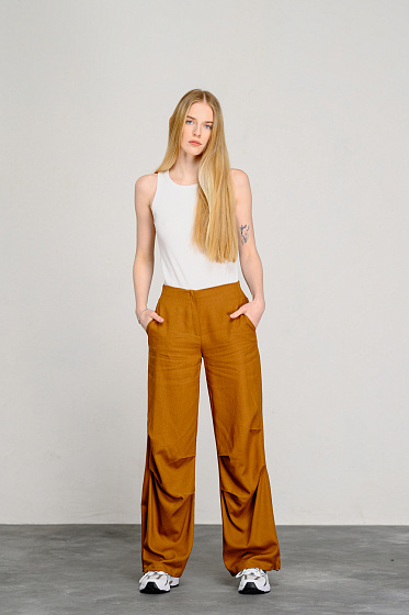 Stylish loose-fitting cargo pants are ideal for creating a comfortable everyday look. The trousers have an elasticated waistband for a perfect fit on any figure, as well as shaped side pockets. Asymmetrical pleats at the knee provide a unique look, while flaps are located on the back of the trousers. The bottom of the pants is fixed with elastic bands, which adds extra comfort and style.