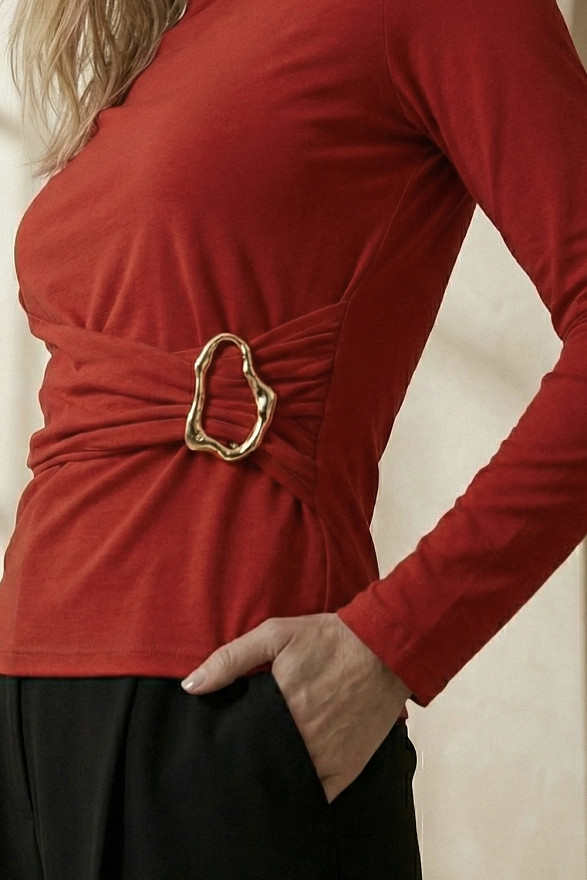 Червоний лонгслів з асиметричною лінією пояса та декоративною пряжкою.