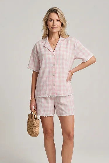 This stylish two-piece suit in Vichy check combines cozy comfort with elegance for summer outings. The set consists of a loose short-sleeve shirt and comfortable shorts with a soft elastic waistband, finished with decorative buttons. The key accent is the delicate lace trim along the edges, adding a light and feminine touch, making it perfect for a relaxed getaway.